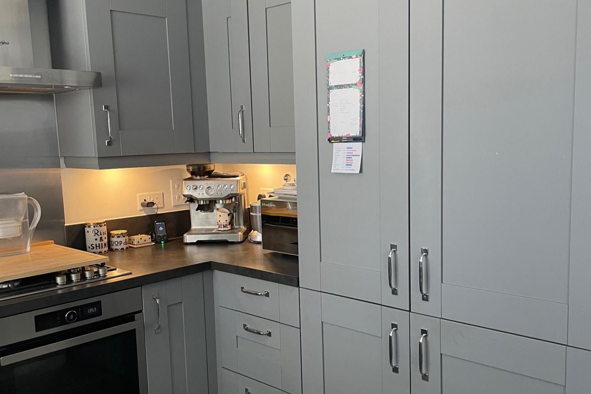 A modern kitchen with grey cabinets, a coffee machine, and a kettle.