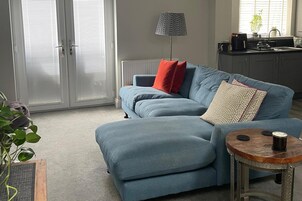 A living room with a sofa, a lamp, a coffee table, and a potted plant.