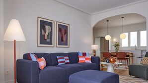 Uma sala de estar moderna com um sofá azul, um abajur vermelho e arte abstrata na parede.