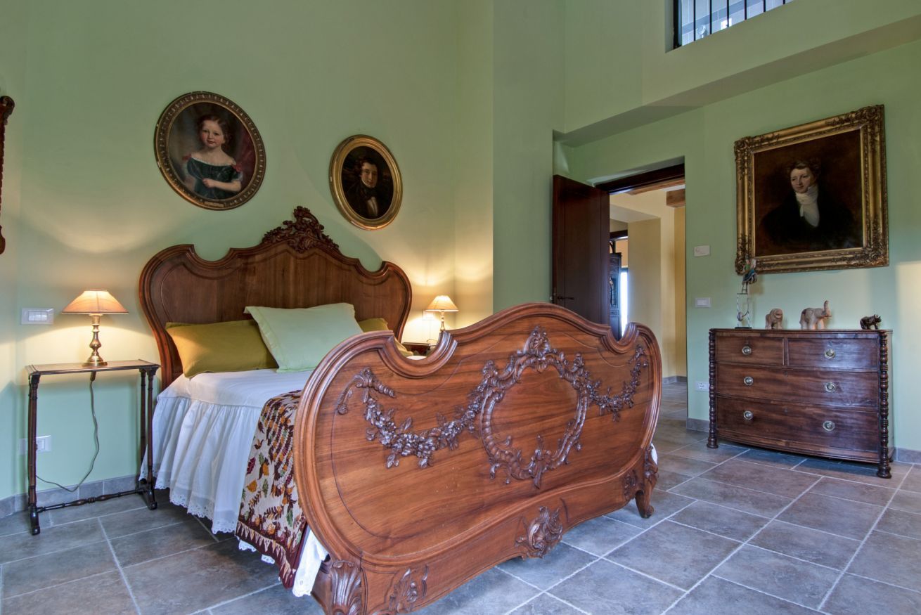 Um quarto com uma cama grande, duas mesas de cabeceira, um penteado e dois retratos emoldurados na parede.