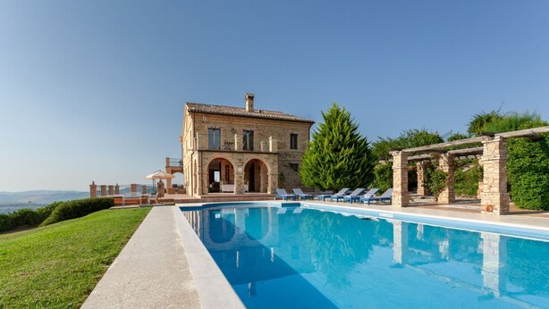 Una piscina con un edificio in pietra sullo sfondo.