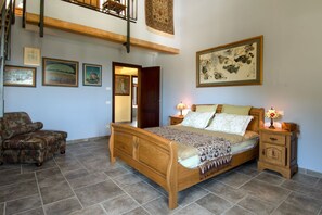 A bedroom with a wooden bed, a chair, a nightstand, and a large painting on the wall. - Villa Smerillo by MMega (Smerillo)