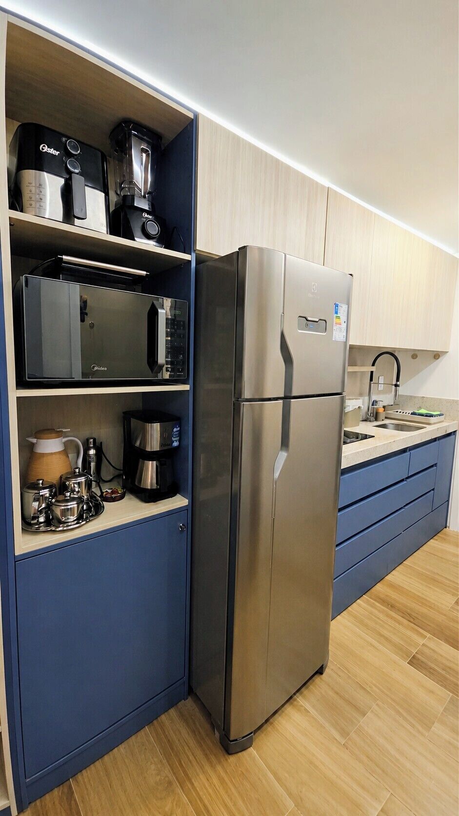 Una cocina con un refrigerador de acero inoxidable, un microondas y una cafetera sobre la encimera.