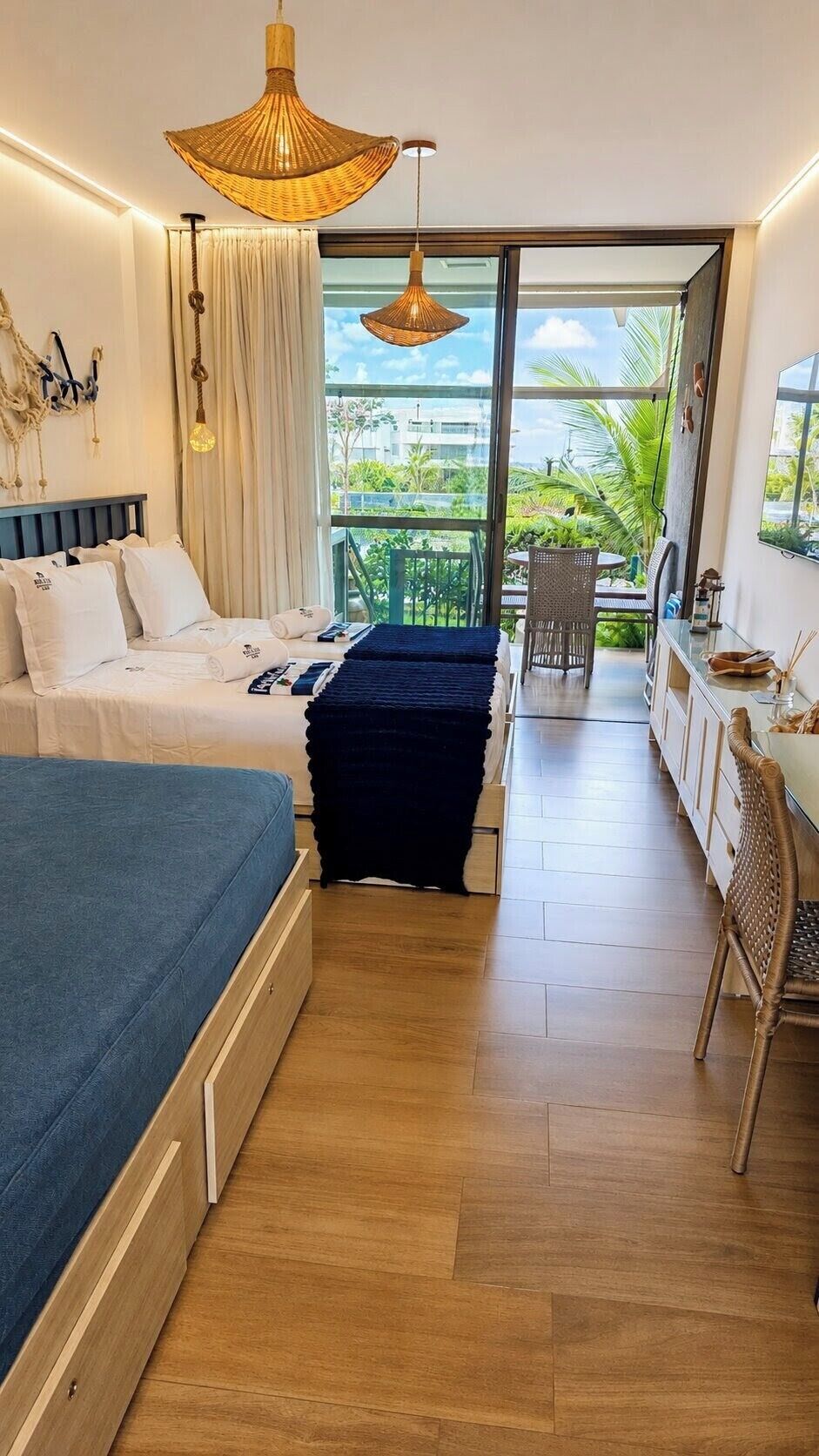 Habitación de hotel con cama, escritorio, silla, balcón y vistas al exterior.