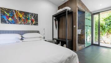 Habitación de hotel moderna con una cama grande, un cuadro en la pared, un armario empotrado y una puerta corrediza de vidrio al exterior.