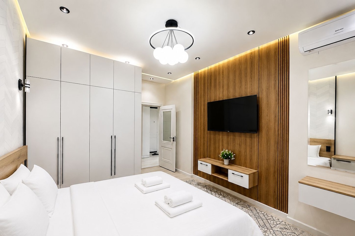A hotel room with a bed, wardrobe, TV, and a mirror.