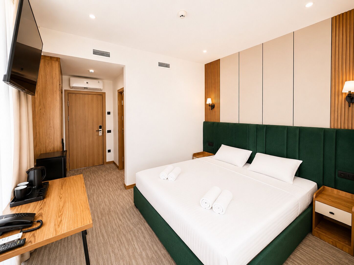 Une chambre d’hôtel équipée d’un lit, d’un bureau, d’un téléphone, d’une télévision et d’une lampe fixée au mur.