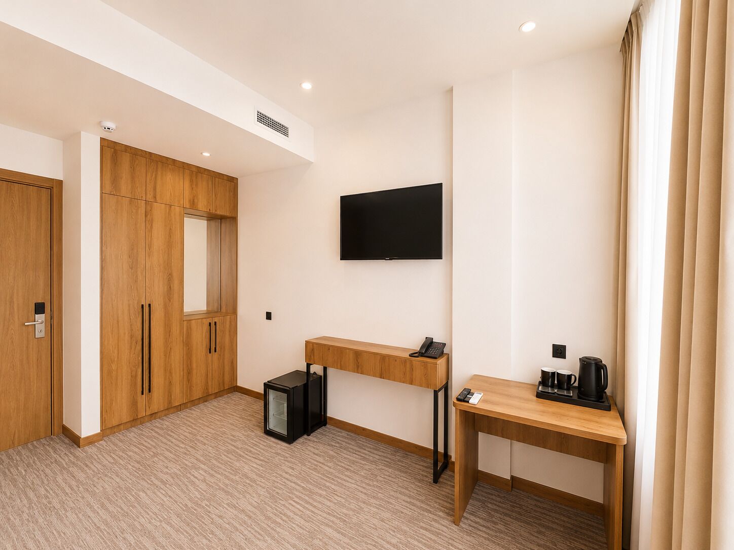 Une chambre d’hôtel avec une armoire en bois, un bureau avec une machine à café, une télévision et un petit réfrigérateur.