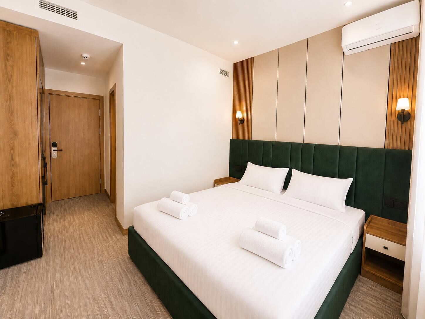 Habitació d'hotel amb un llit gran, un armari de fusta, una taula de nit i un aparell d'aire condicionat.