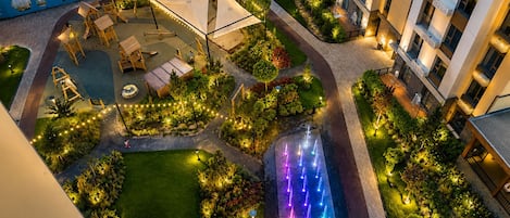 A hotel courtyard with outdoor seating, a water feature, and well-maintained landscaping.