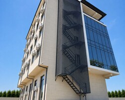 A modern building with a glass facade, a metal staircase, and multiple air conditioning units.