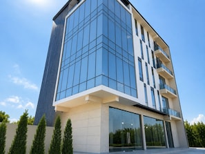 Un edificio moderno con fachada de vidrio, techo plano y varios balcones.