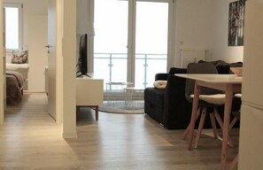 A modern living room with a dining area, a sofa, a TV, and a balcony. - Kuschelnest Feldberg – Hochschwarzwald Card Included – My SWH (Feldberg)