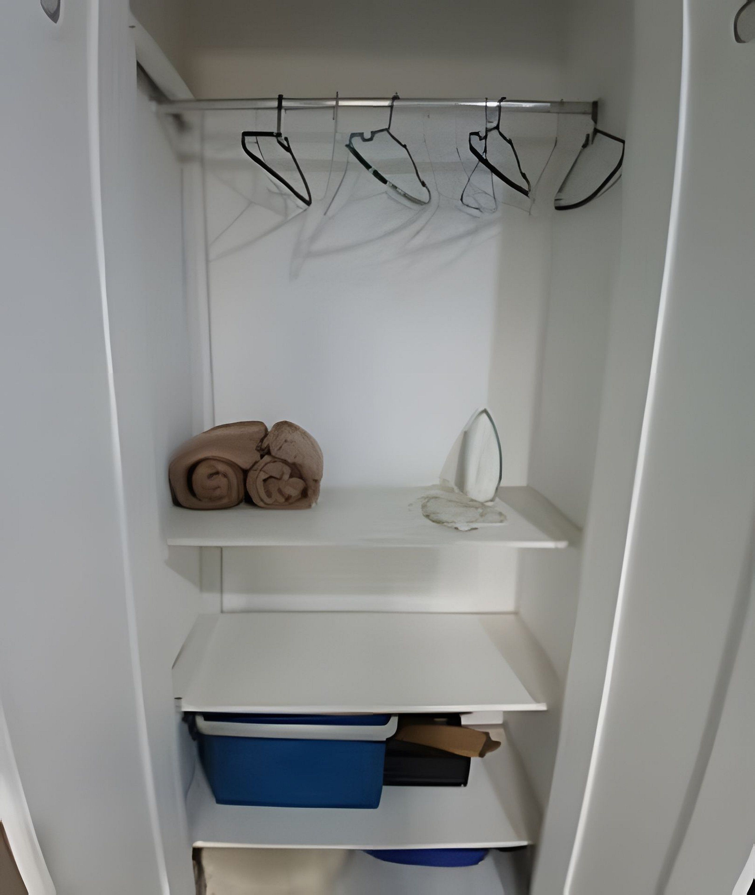 A white closet with shelves, a hanging rod, and storage boxes.