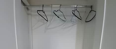 Un armario blanco con estantes, una barra para colgar ropa y cajas de almacenamiento.