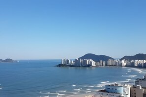 Eine Küstenlandschaft mit Hochhäusern, einem Strand und Bergen im Hintergrund.