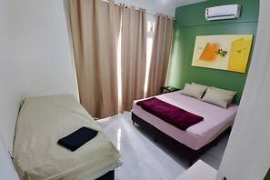 A bedroom with a bed, a bedside table, a chair, a window with curtains, and an air conditioning unit on the wall. - SHB - Delicioso apartamento no Guarujá (Guarujá)