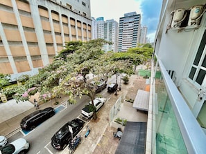 Un edificio de varios pisos con una zona de estacionamiento, una calle arbolada y una vista despejada de los edificios altos circundantes.