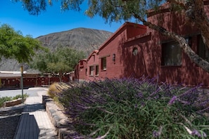 A red building with a wooden deck and lavender plants. - Eco Hotel Posta de Purmamarca (Purmamarca)