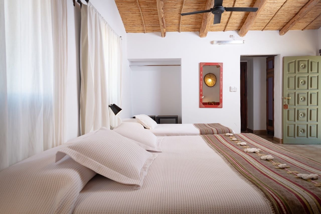 Un dormitorio con cama, mesita de noche, lámpara, reloj de pared y una puerta verde.