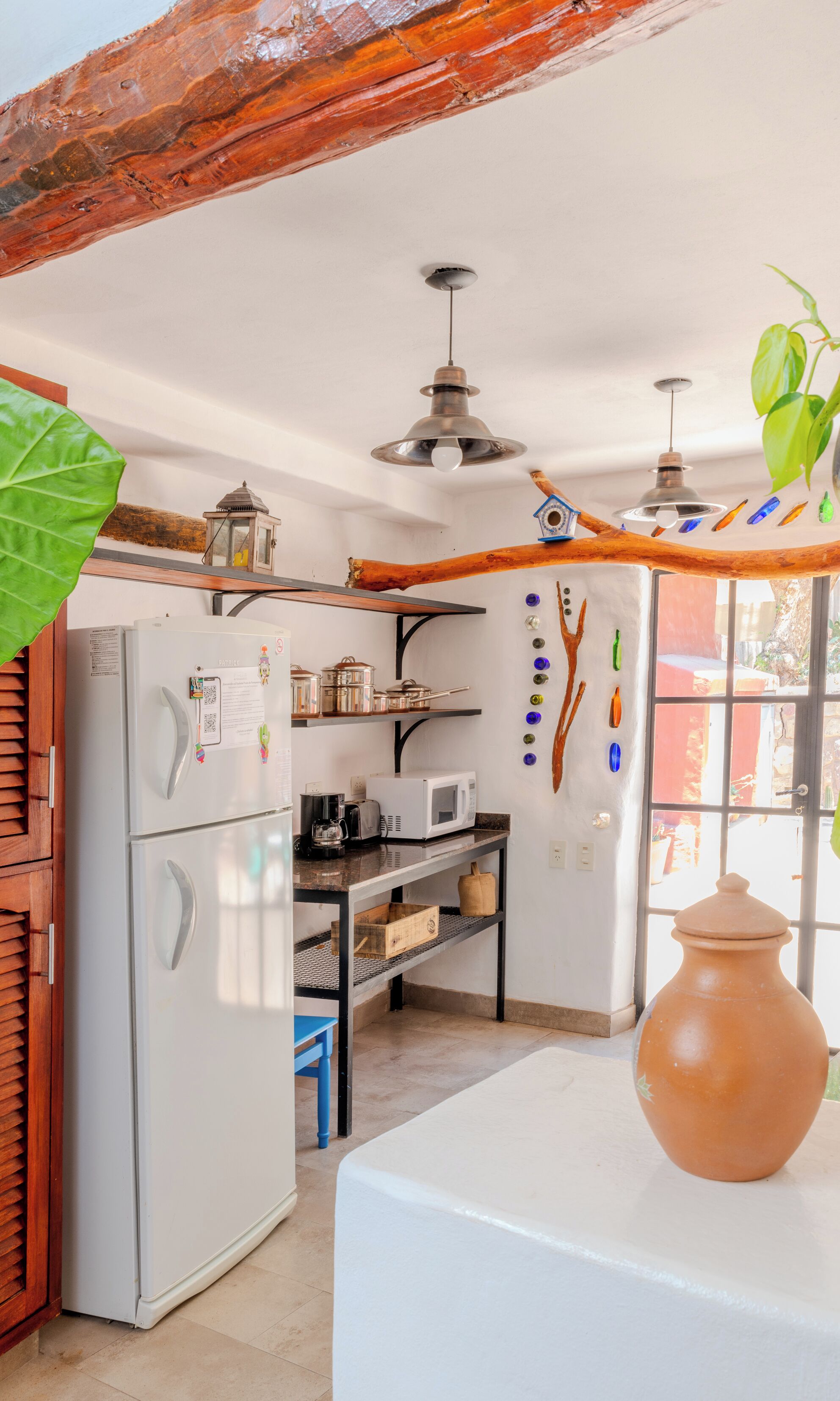 A compact kitchen with a refrigerator, microwave, and wooden shelves.