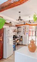 Una cocina compacta con refrigerador, microondas y estantes de madera.