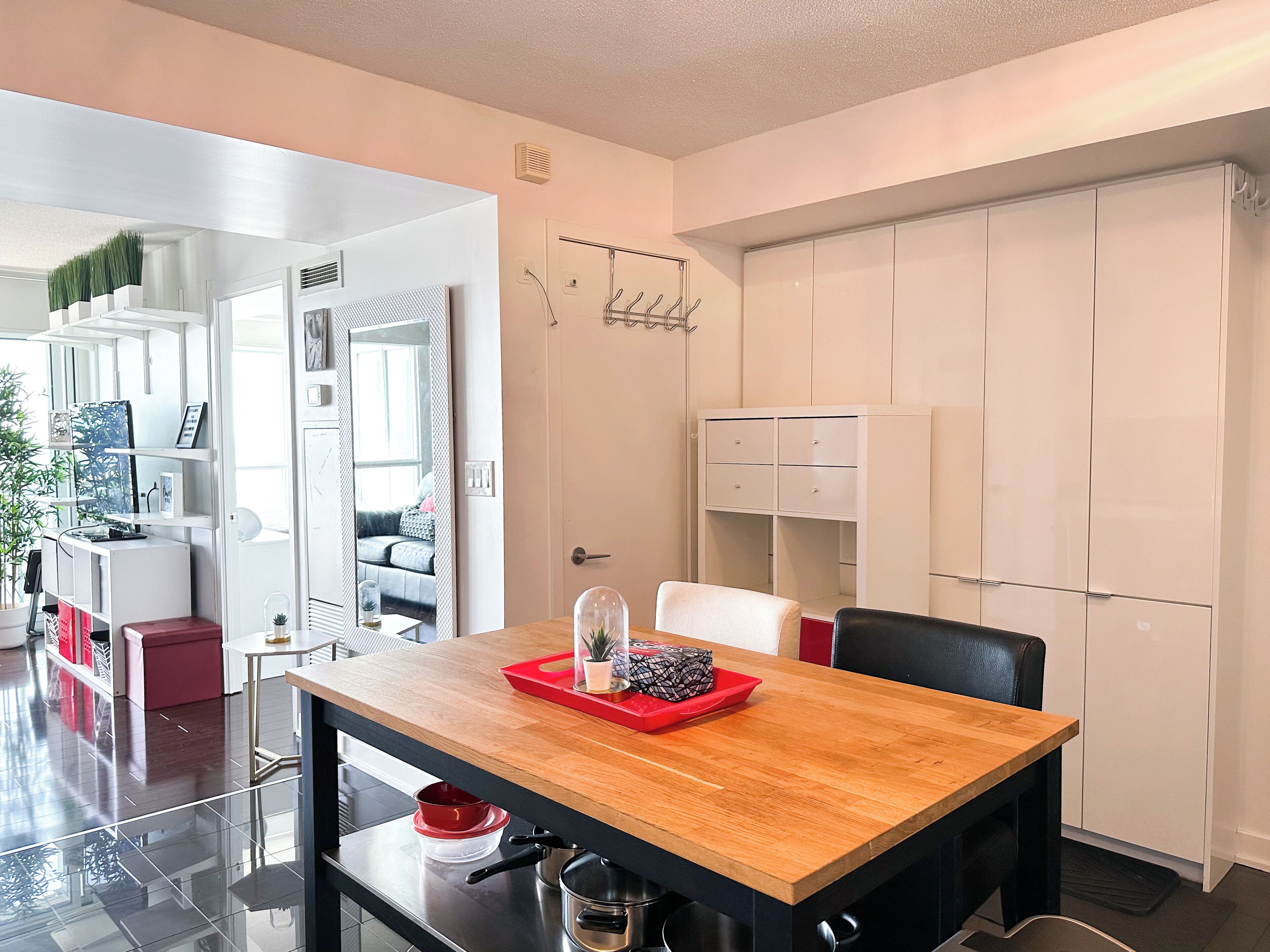 A modern kitchen with a wooden table, black chairs, and white cabinets.