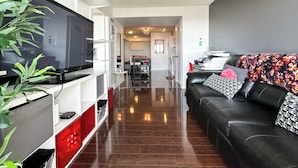 A modern living room with a black leather sofa, a flat-screen TV, and a dining area in the background. - City Central Residences Downtown Toronto (Toronto)