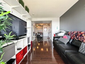A modern living room with a black leather sofa, a flat-screen TV, and a dining area in the background. - City Central Residences Downtown Toronto (Toronto)
