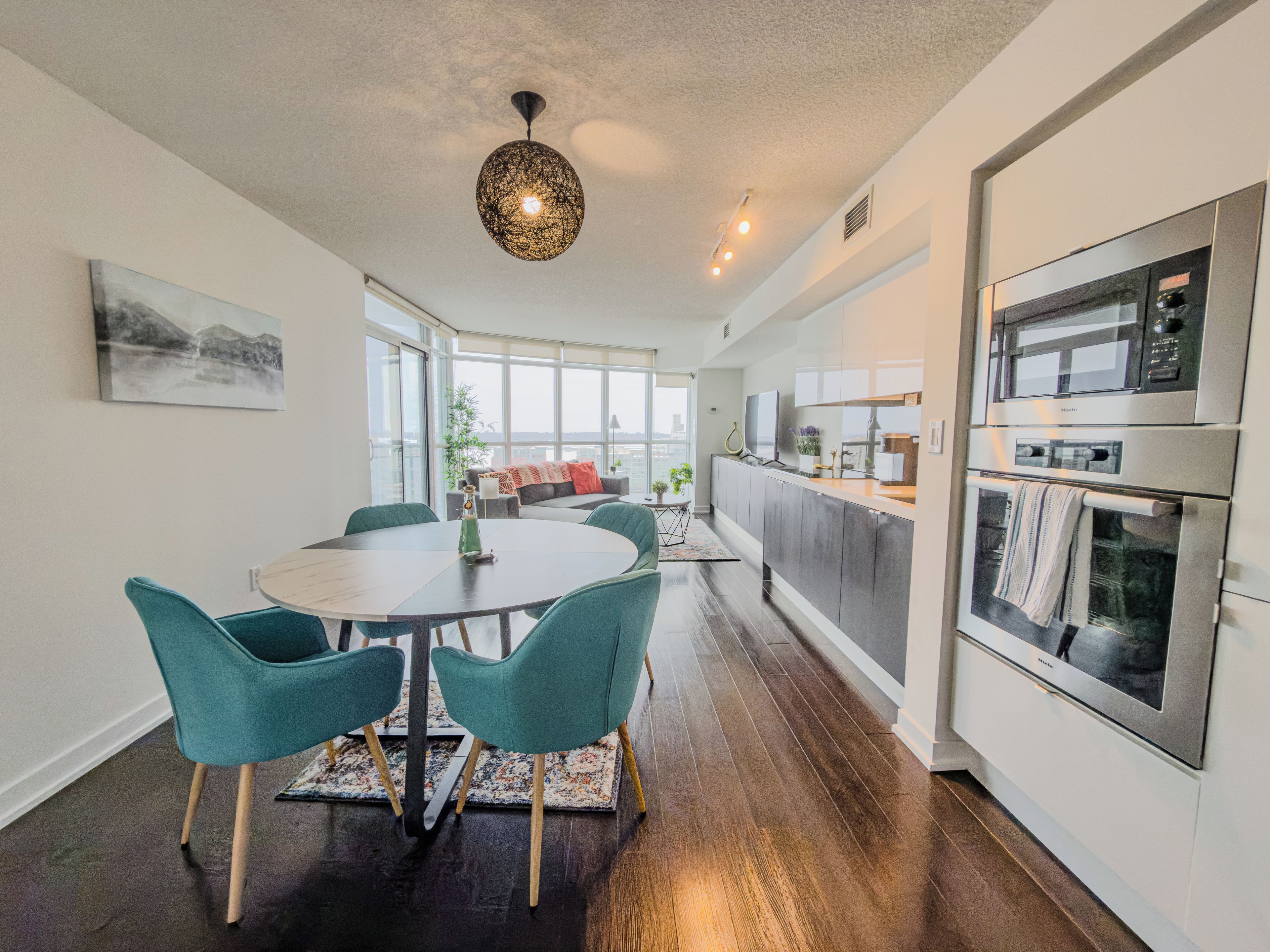 A modern kitchen with a dining area, large windows, and a view of the city.