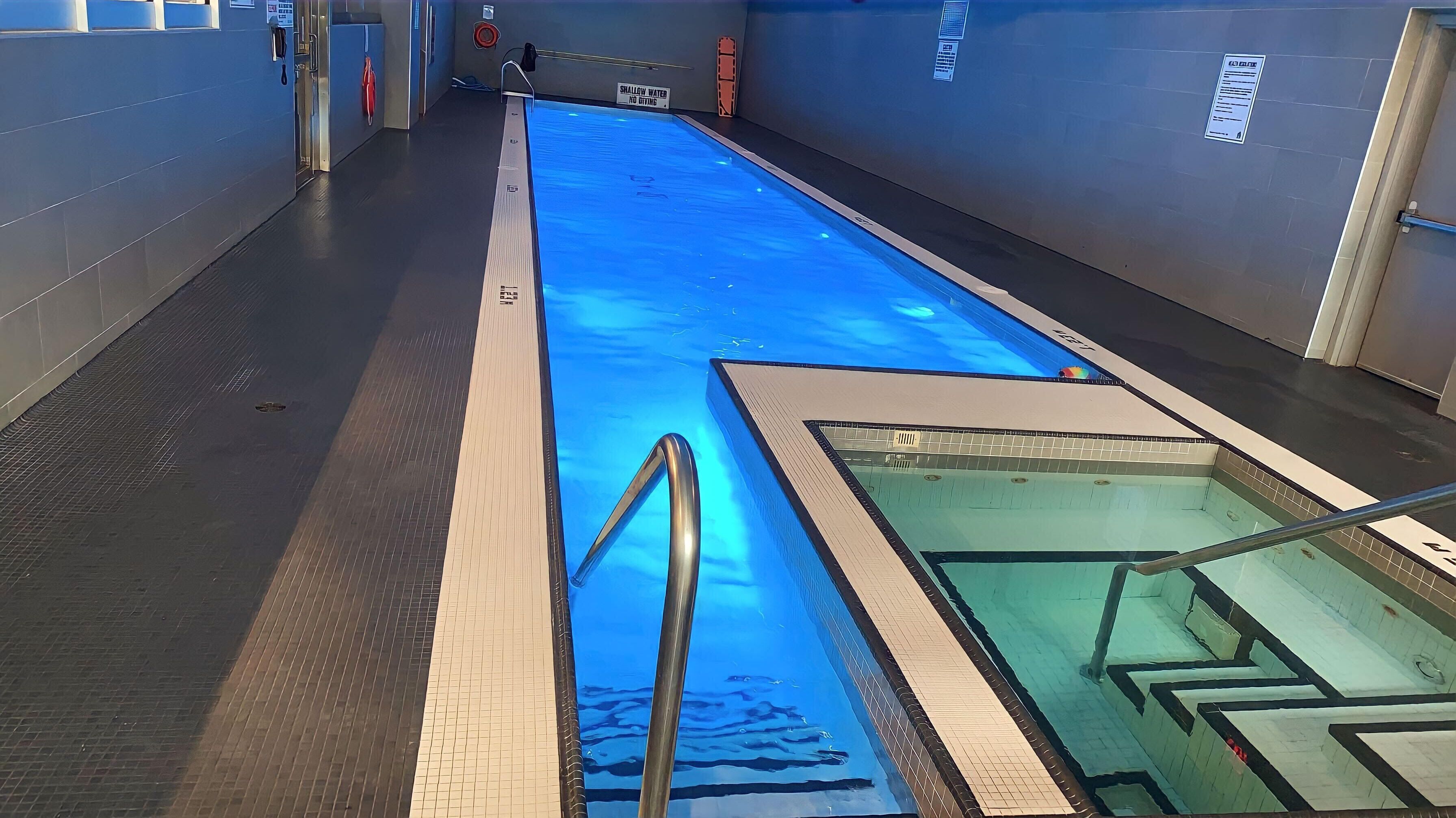 A swimming pool with a blue water feature, a lifeguard chair, and a sign indicating shallow water.