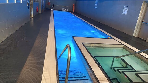 A swimming pool with a blue water feature, a lifeguard chair, and a sign indicating shallow water. - City Central Residences Downtown Toronto (Toronto)
