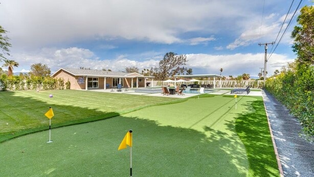 Um campo de golfe com um clube, uma piscina e uma área coberta com assentos.