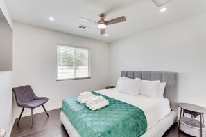 A hotel room with a bed, a chair, a small table, a ceiling fan, and a window. - Private Backyard Oasis-Pool/Bocci/Golf (Palm Springs)