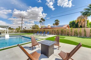 A swimming pool with lounge chairs and a table, surrounded by a well-maintained lawn and a brick wall. - Private Backyard Oasis-Pool/Bocci/Golf (Palm Springs)