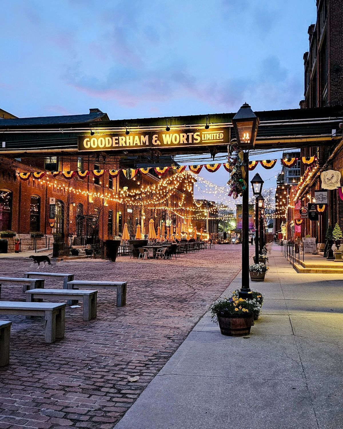 A cobblestone street with outdoor seating and a sign for Gooderham & Worts Limited.