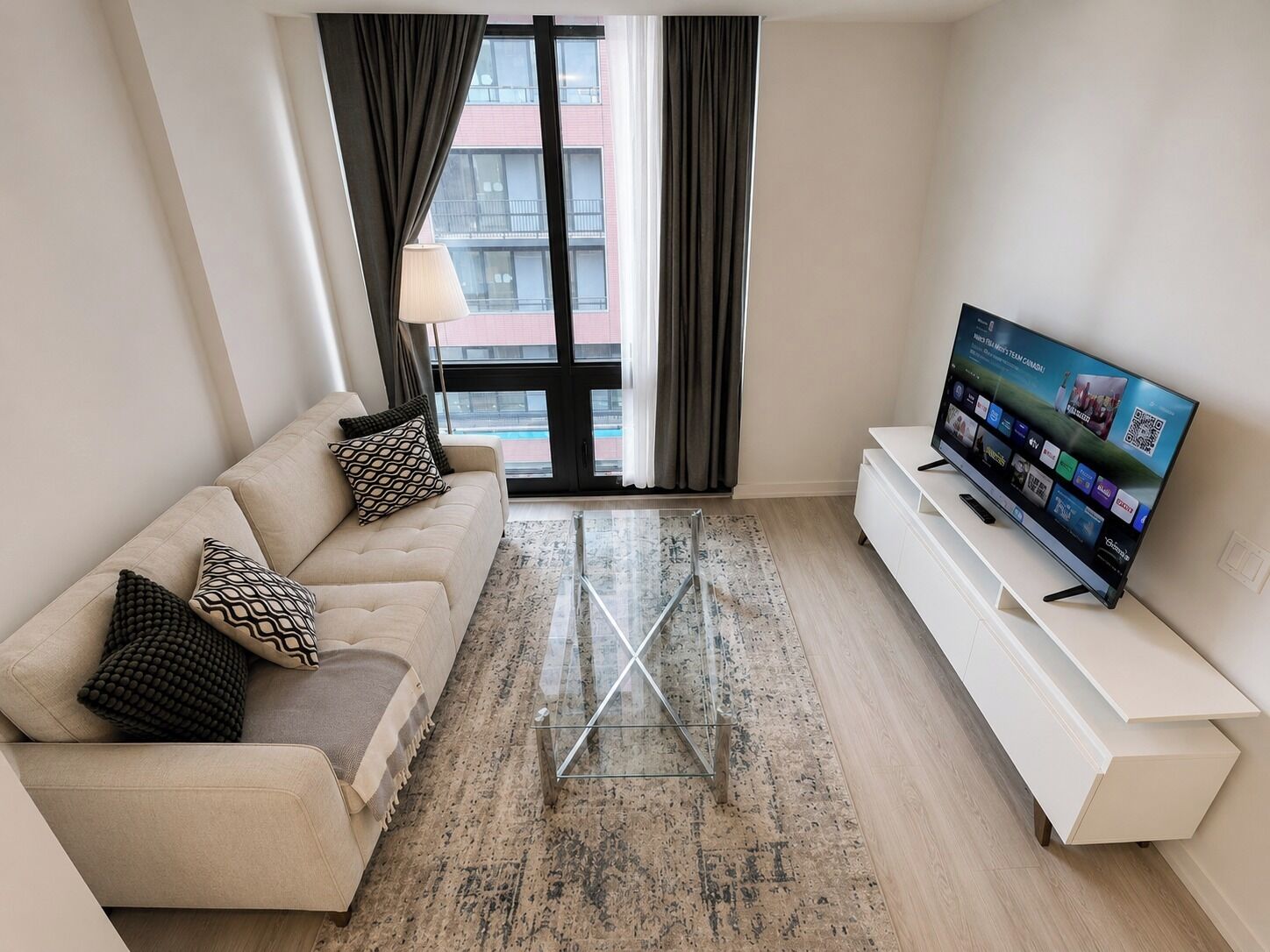 A modern living room with a sofa, TV, and a glass coffee table.