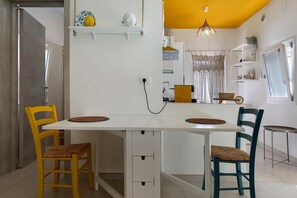 A compact kitchen with white cabinetry, a dining table with four chairs, and a hanging light fixture. - Holiday Home 'Vacanza Le Dune- Sole' with Private Terrace and Air Conditioning (Maruggio)