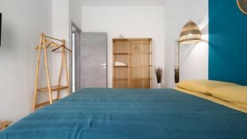 A bedroom with a bed, a wardrobe, a hanging rack, and a lamp.