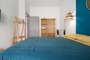 Quarto com cama, guarda-roupa, cabideiro e luminária.