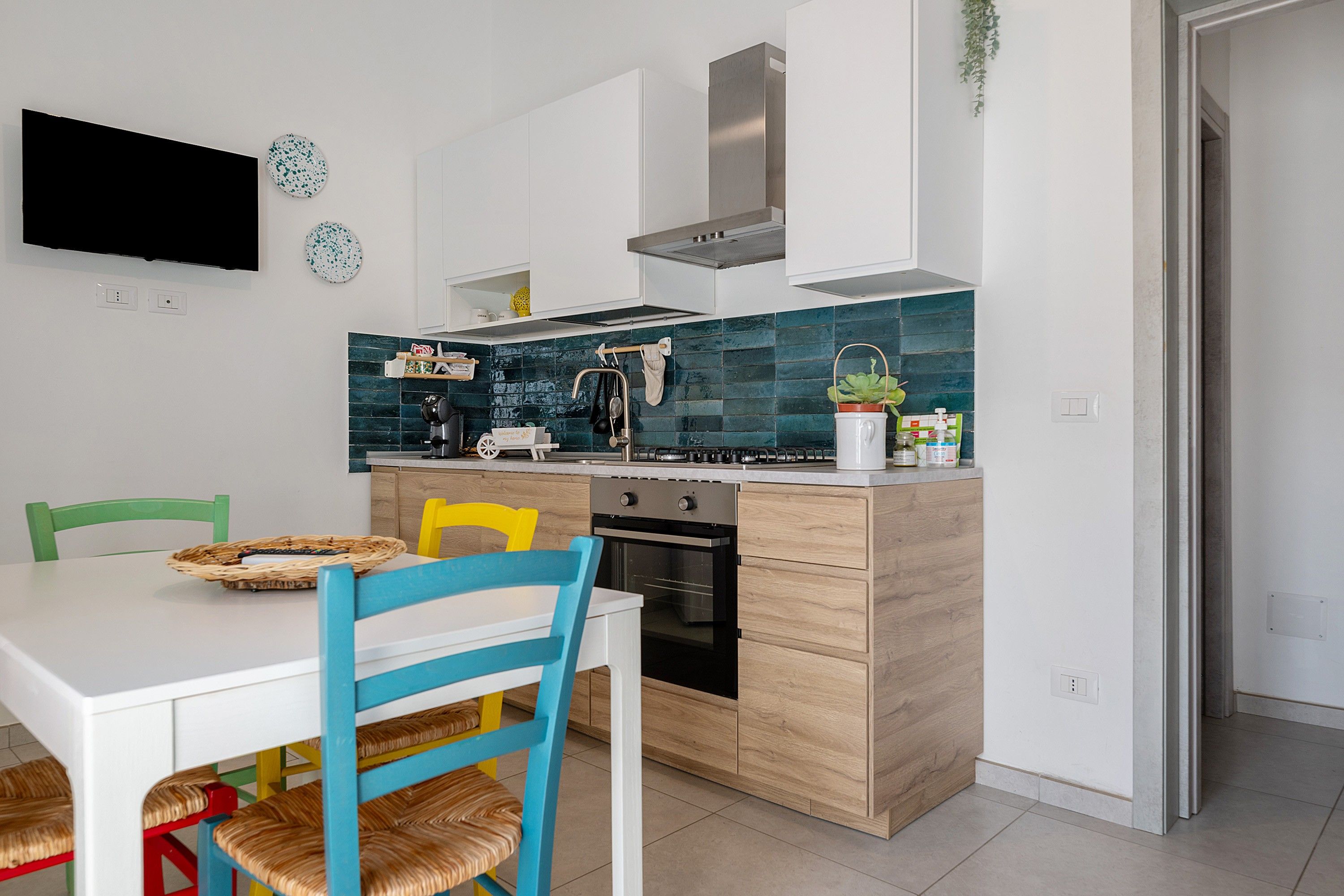 A modern kitchen with a dining table, chairs, and a TV mounted on the wall.