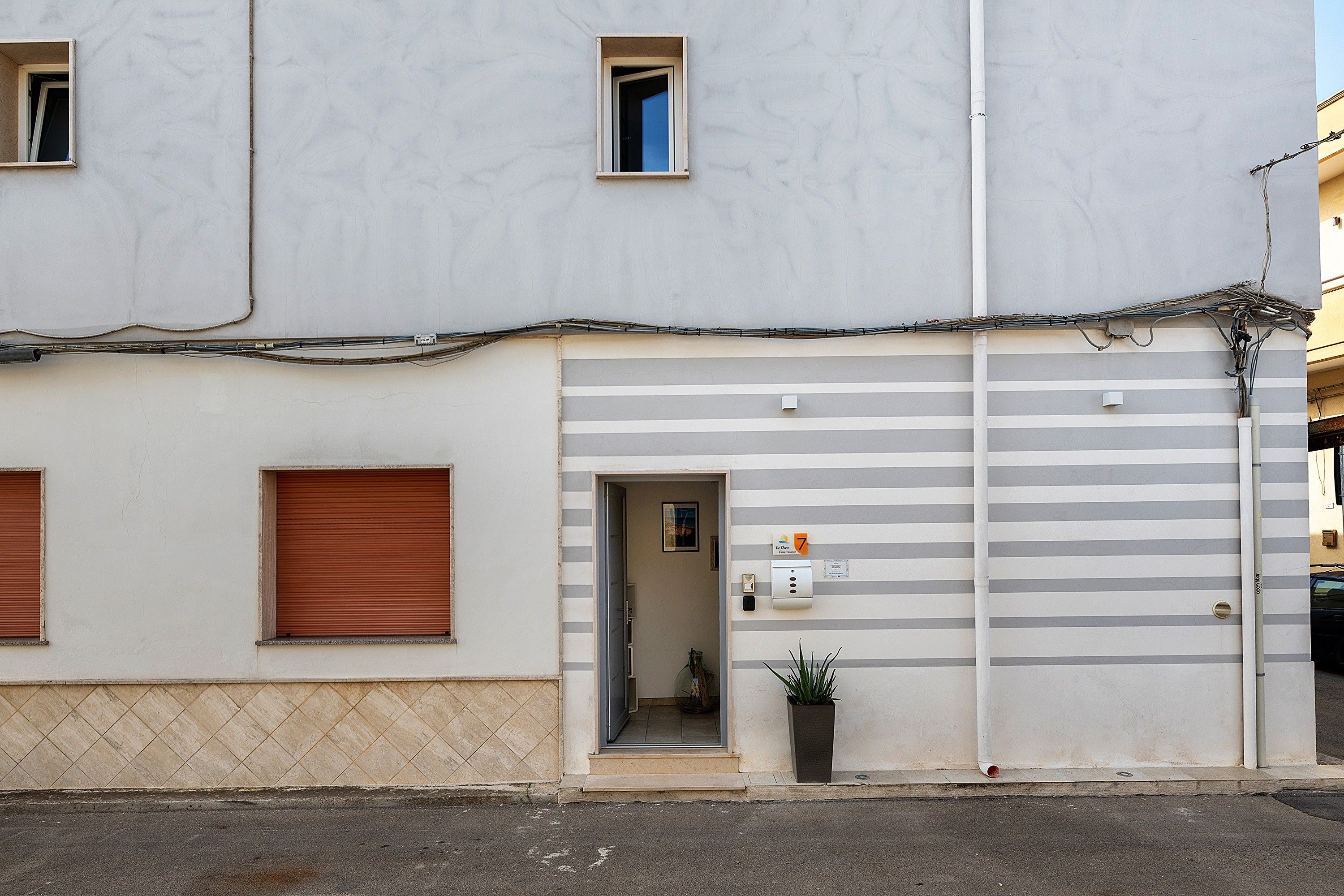 A building with a ground floor entrance, a visible door, and a small potted plant outside.
