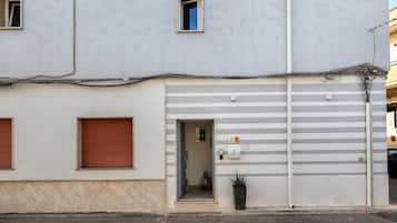 A building with a ground floor entrance, a visible door, and a small potted plant outside.