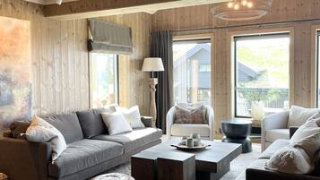 A cozy living room with a sofa, armchairs, ottomans, a coffee table, and a lamp.