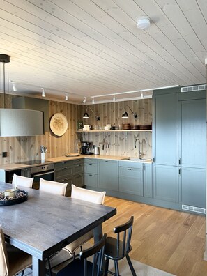 Une cuisine moderne avec un revêtement mural en bois, un îlot central et des appareils électroménagers intégrés.