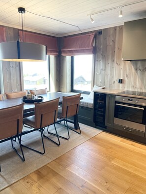Une cuisine moderne avec un coin repas, un plancher en bois et de grandes fenêtres.