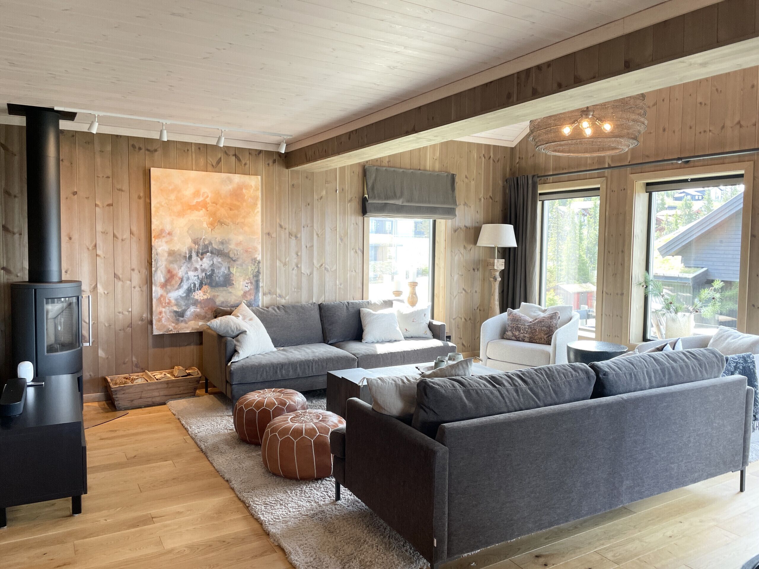A modern living room with a fireplace, grey sofas, and a large abstract painting.