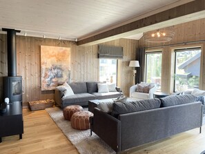 A modern living room with a fireplace, grey sofas, and a large abstract painting.