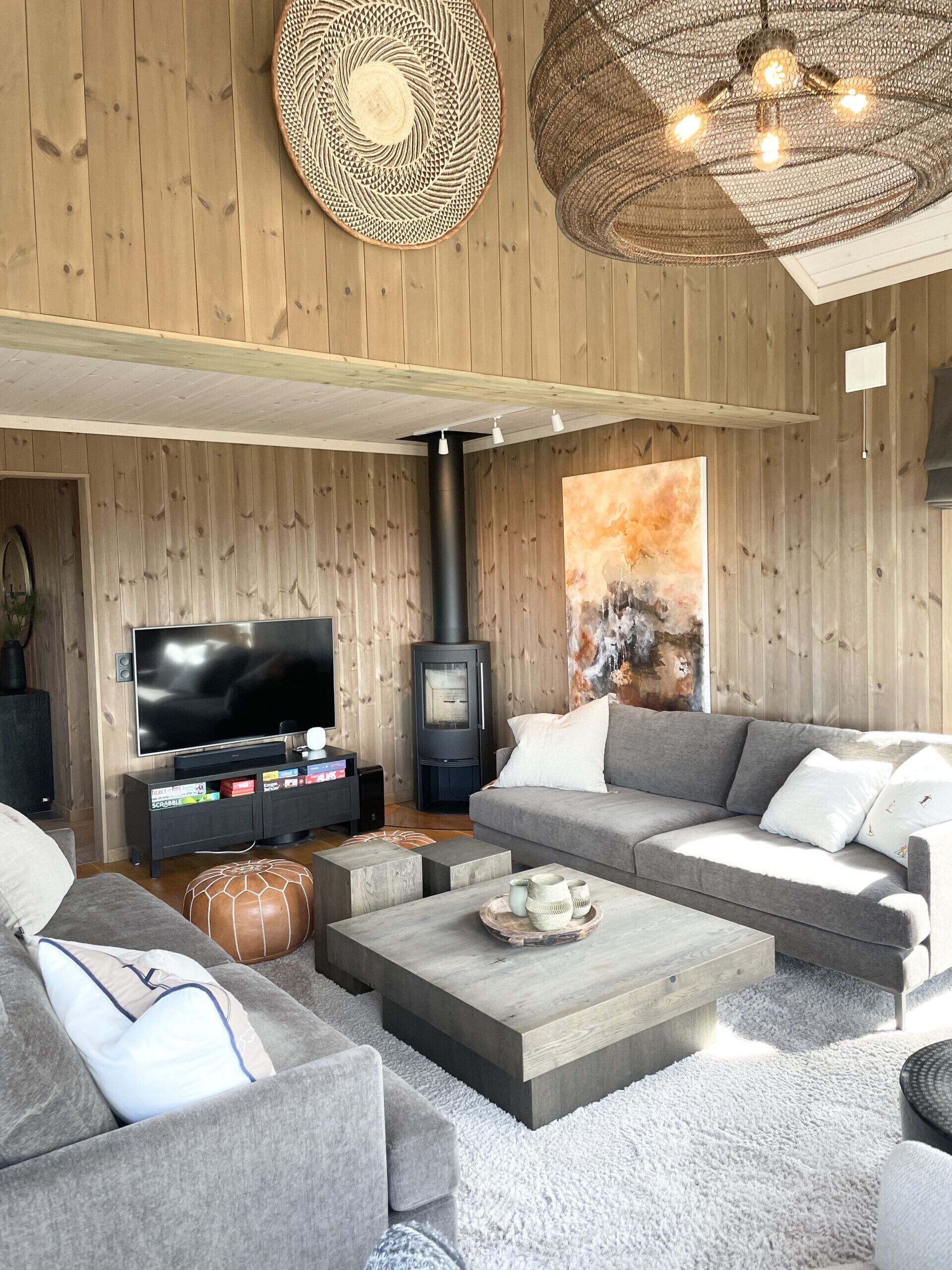 Un salón moderno con un televisor de pantalla plana grande, una chimenea y un conjunto de sofá gris.