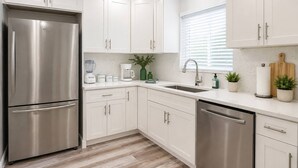 A modern kitchen with stainless steel appliances, white cabinetry, and a window with blinds. - Comfy Home 4 Beds Steps to Hard Rock Stadium Free Parking Miami Gardens (Miami)